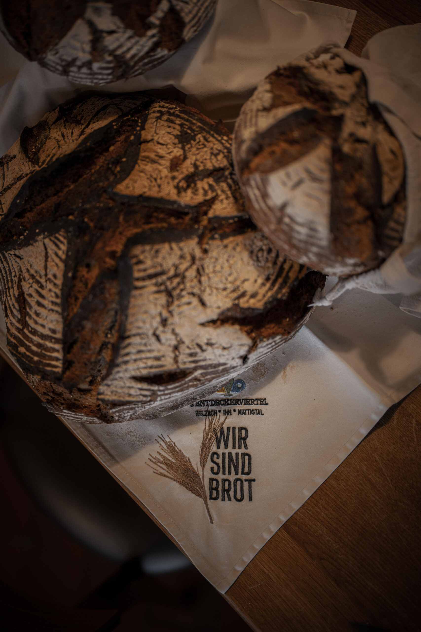 Selbstgemachtes, krosses, knusprig braunes Roggennatursauerteig Brot auf beiger Serviette von der Entdeckerviertel Kooperation Wir sind Brot