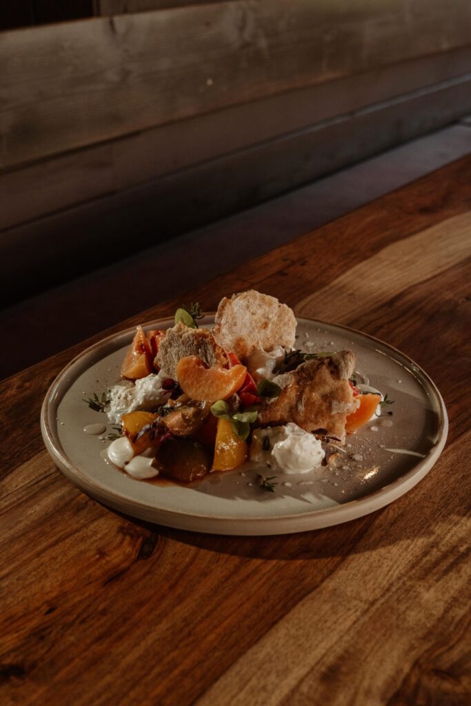 Burrata mit Pfirsich, Tomate und Kräutern auf einem Keramikteller