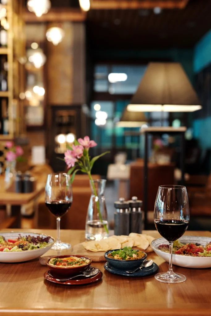 Zwei Gläser Rotwein und kleine Gerichte auf einem Tisch im Noras