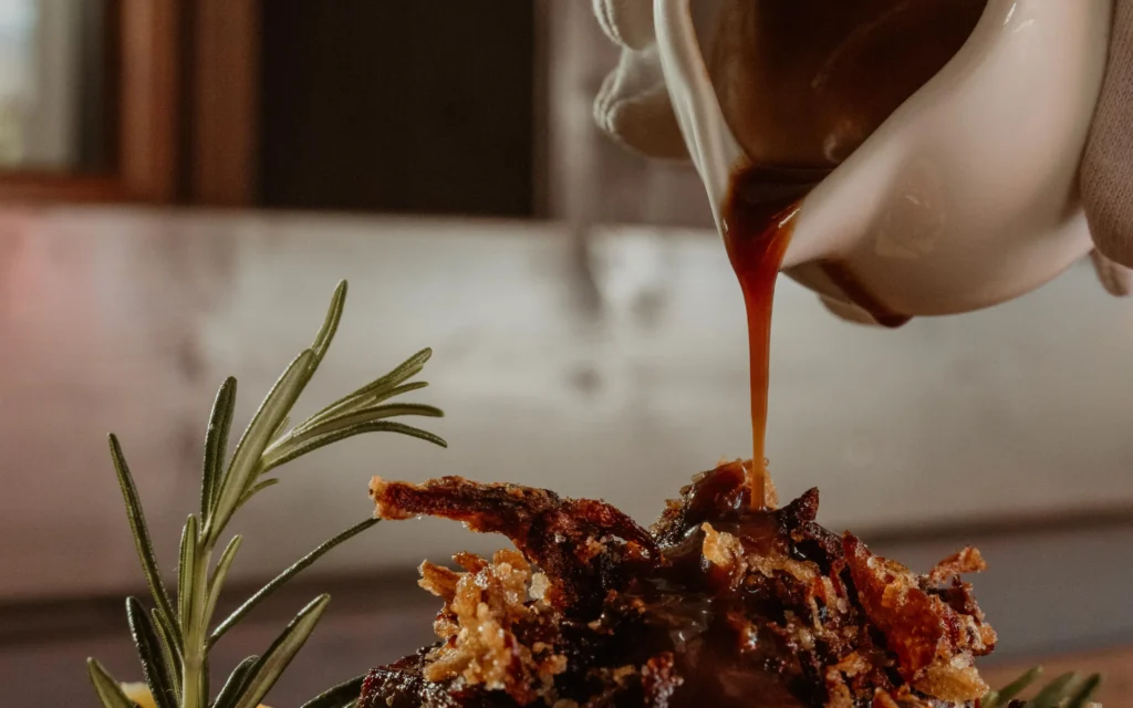 Jus wird am Tisch über geschmorte Short Rib vom Wagyu gegossen